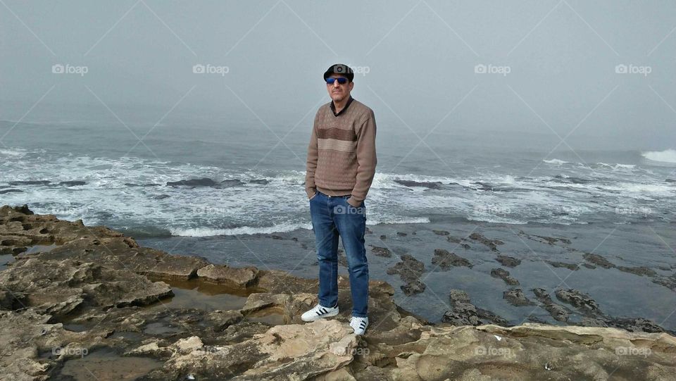 I m standing on a rock near the beach.