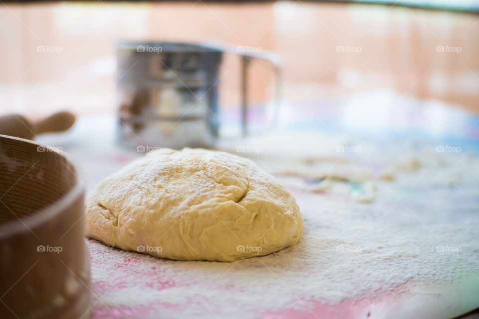 On the table lies a pastry for pies with sprinkled flour and a seeder for flour. Written to bake on the table.