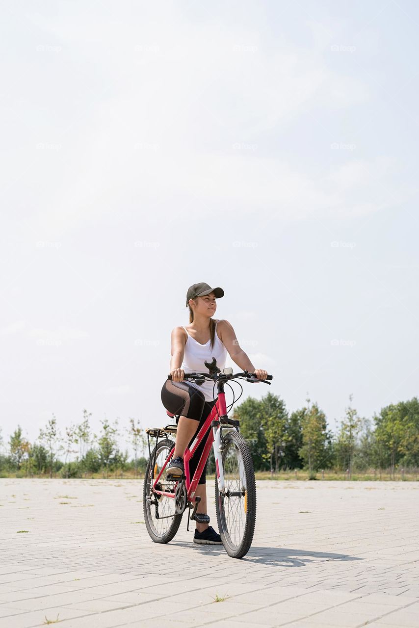 woman in sports clothes and cap riding her bicycle