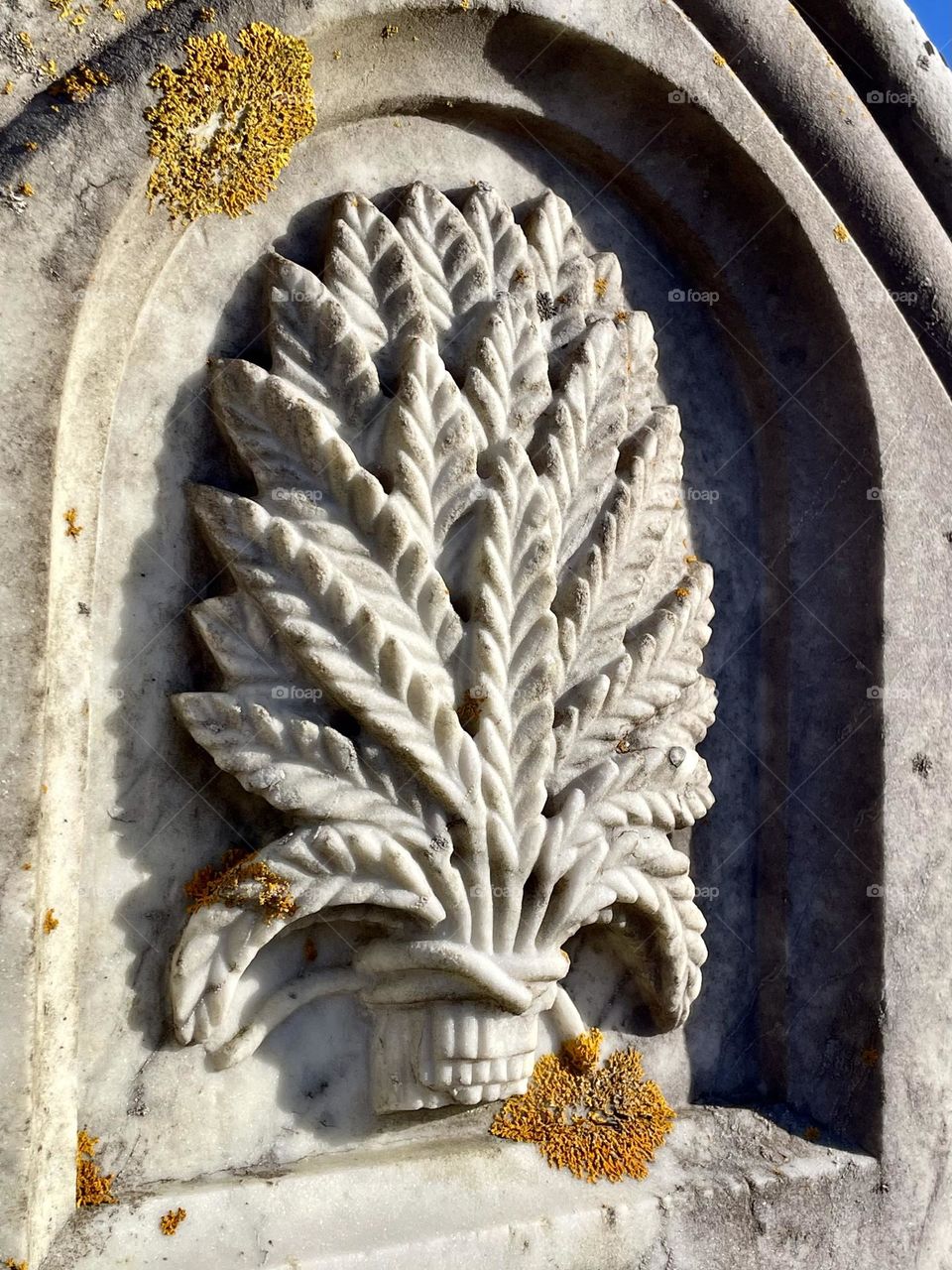 A carved symbol of a sheaf of wheat on gravestone marker.