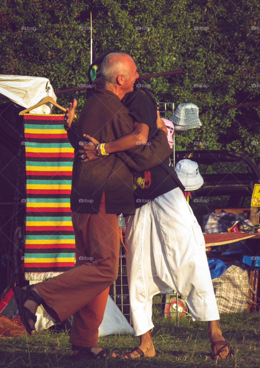 Two old friends greet each other warmly at a summer festival