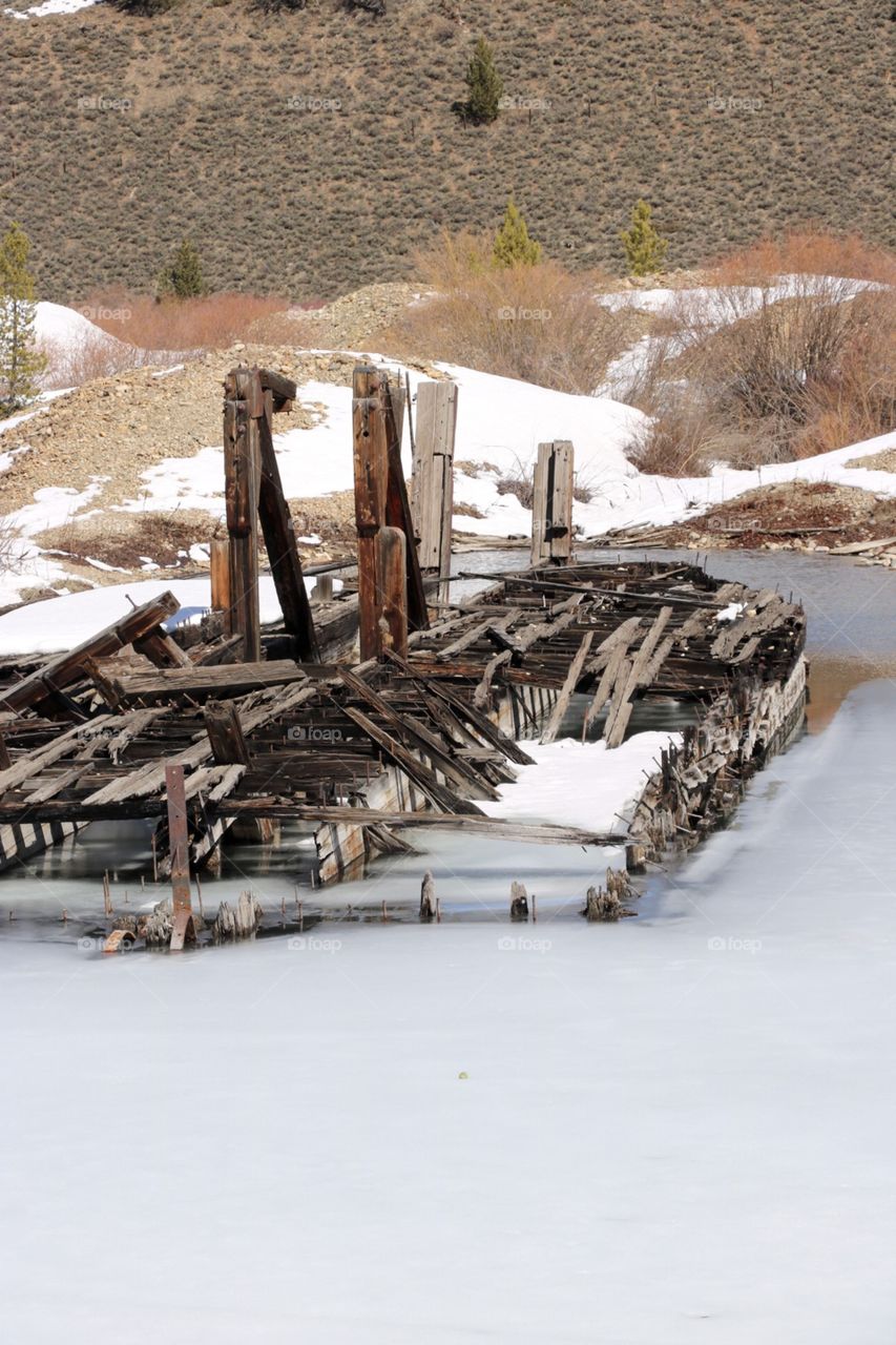 An abandoned gold mining dredge, frozen in a mountain lake in Colorado. 