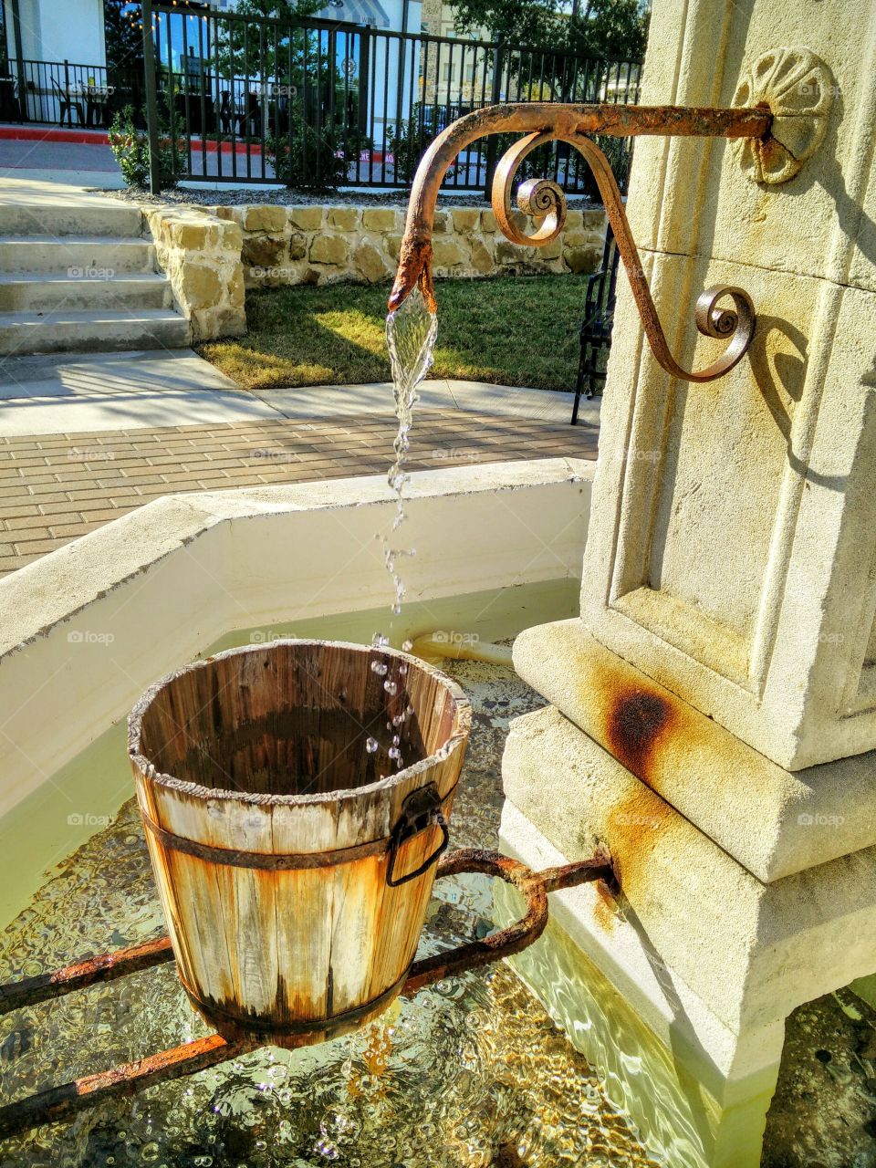 a wooden bucket catches water in a fountain