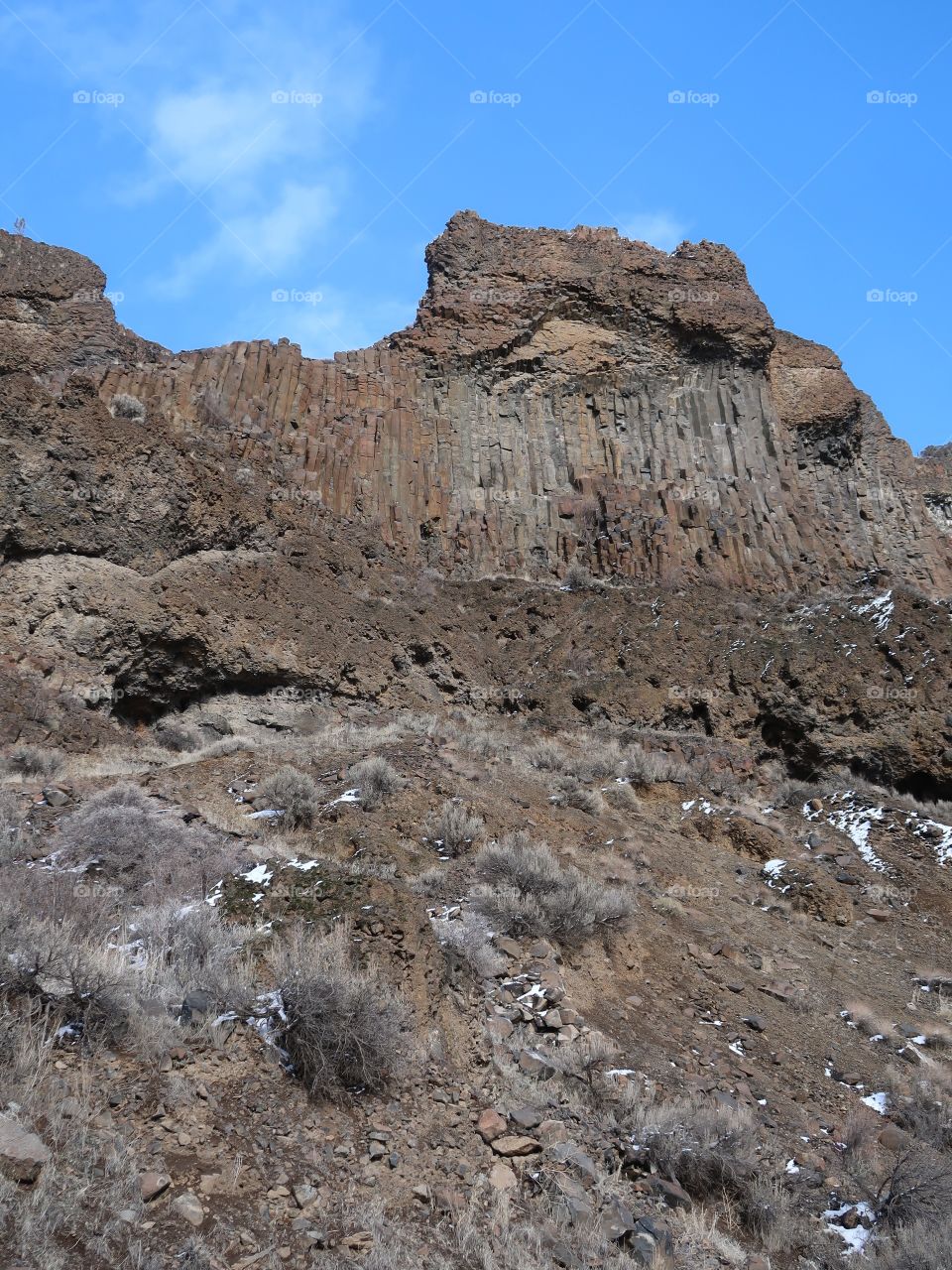 Cliffs of basalt stick out with just a bit of snow on the ground on a beautiful sunny winter day in Central Oregon. 