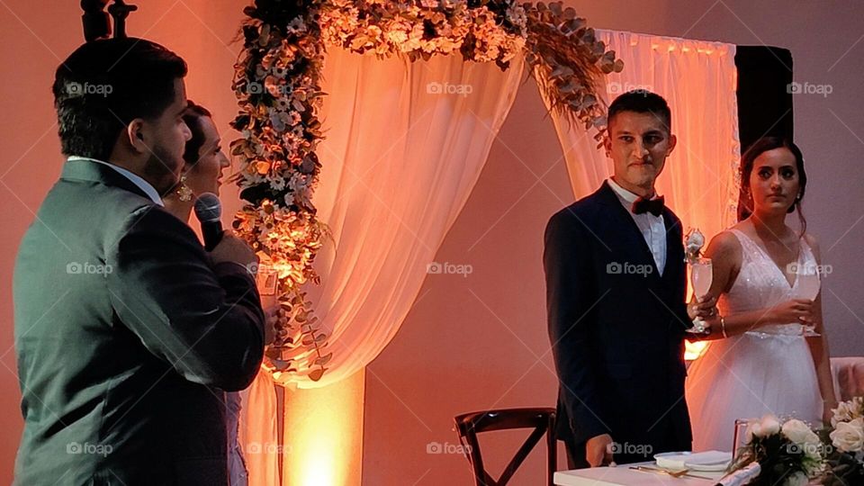 Man giving a words with a microphone to his friend just married while looks to the eyes of each other.