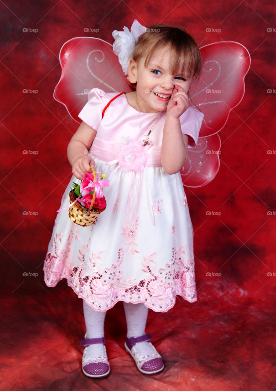portrait of happy little girl in fairy costume on a red background