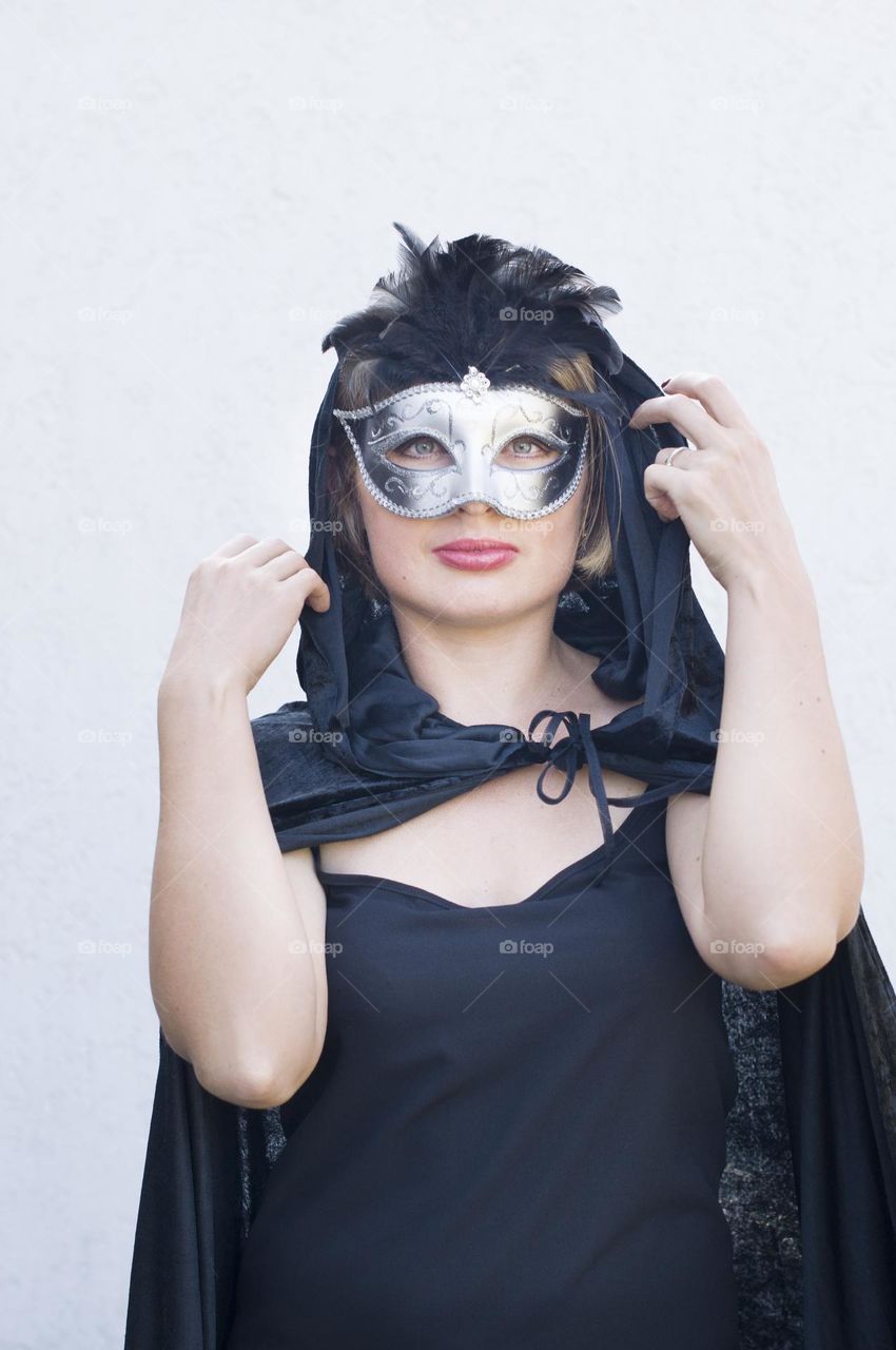 beautiful mysterious girl in black cloak and carnival mask, mardi gras parade