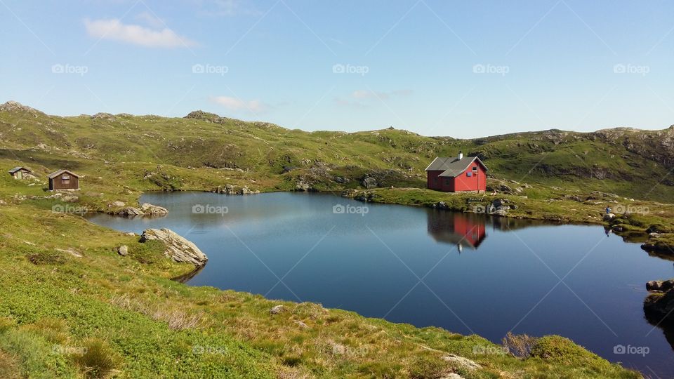 Reflection of house on pond near mountain