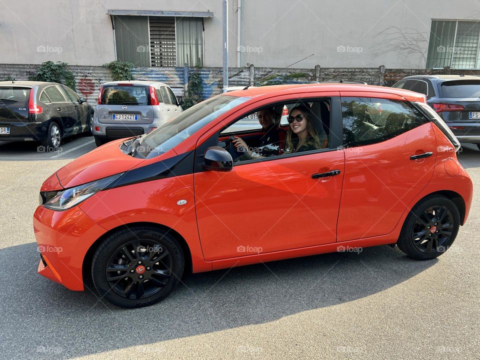 Orange car with woman blonde hair driving 