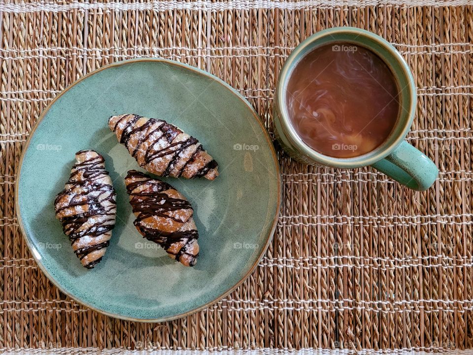 Morning time, simple breakfast of chocolate croissants and coffee on bamboo placemat