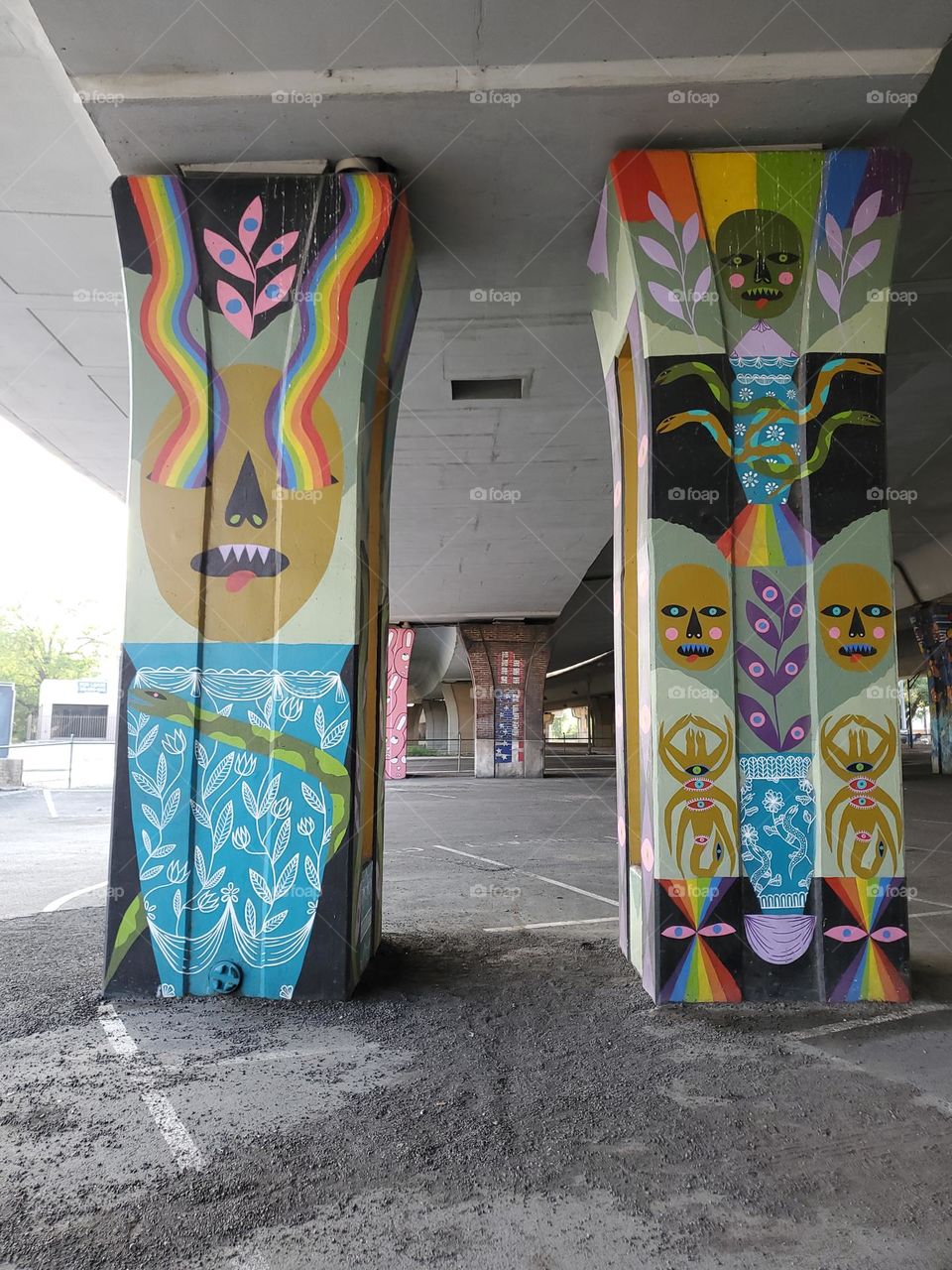 Colorful urban street art on cement pillars of a highway underpass.