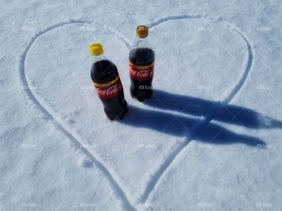 Coca Cola bottles inside a heart drawn in the snow