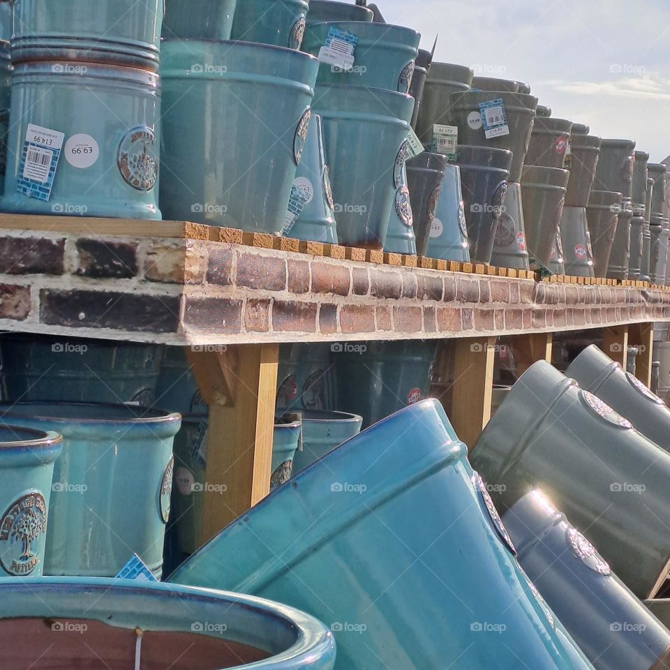 ceramic blue grey pots on shelves in line. garden centre