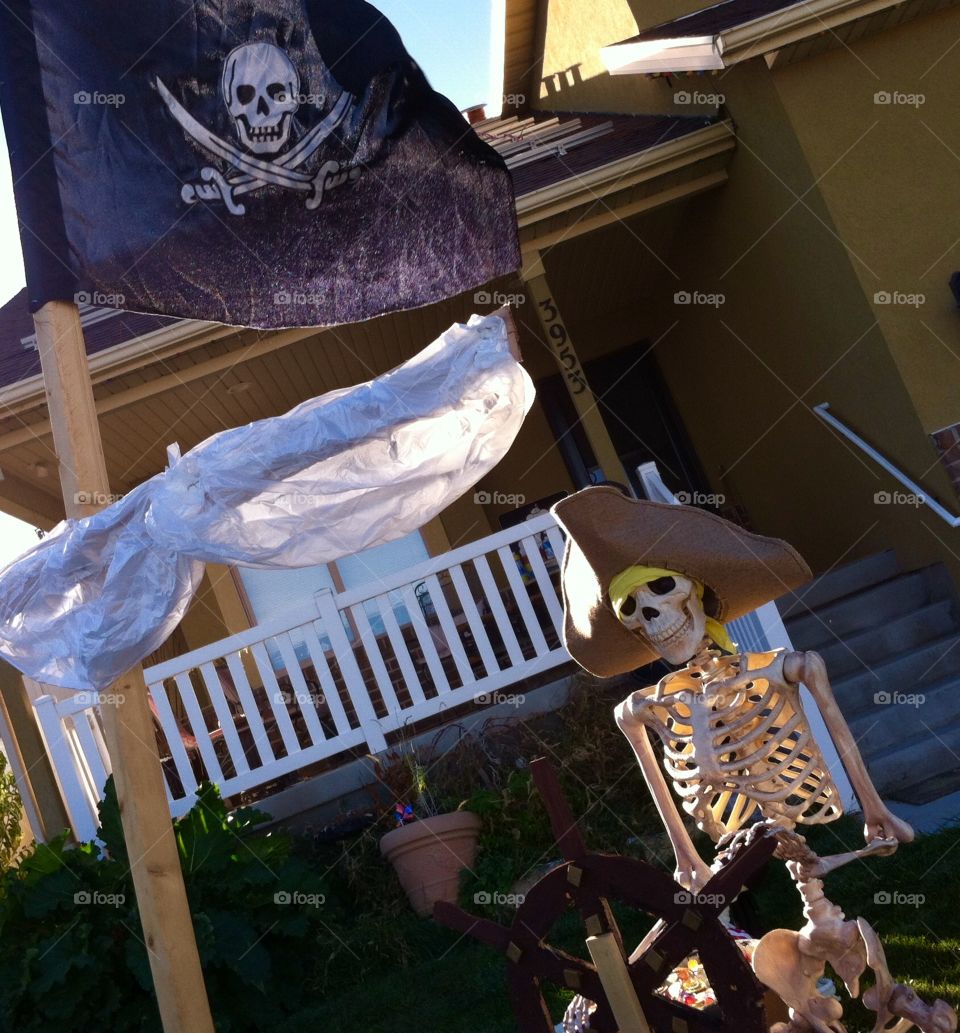 Skeleton dressed as pirate sailing homemade boat 