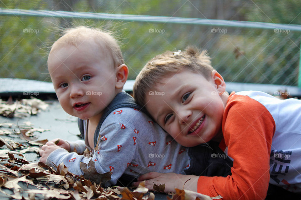 Two cute boys lying on dry leaves