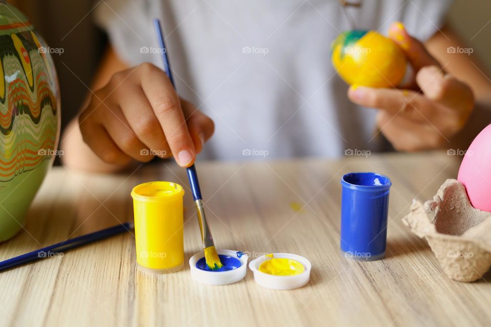Blue vs yellow. child paints eggs, yellow and blue paint, creativity