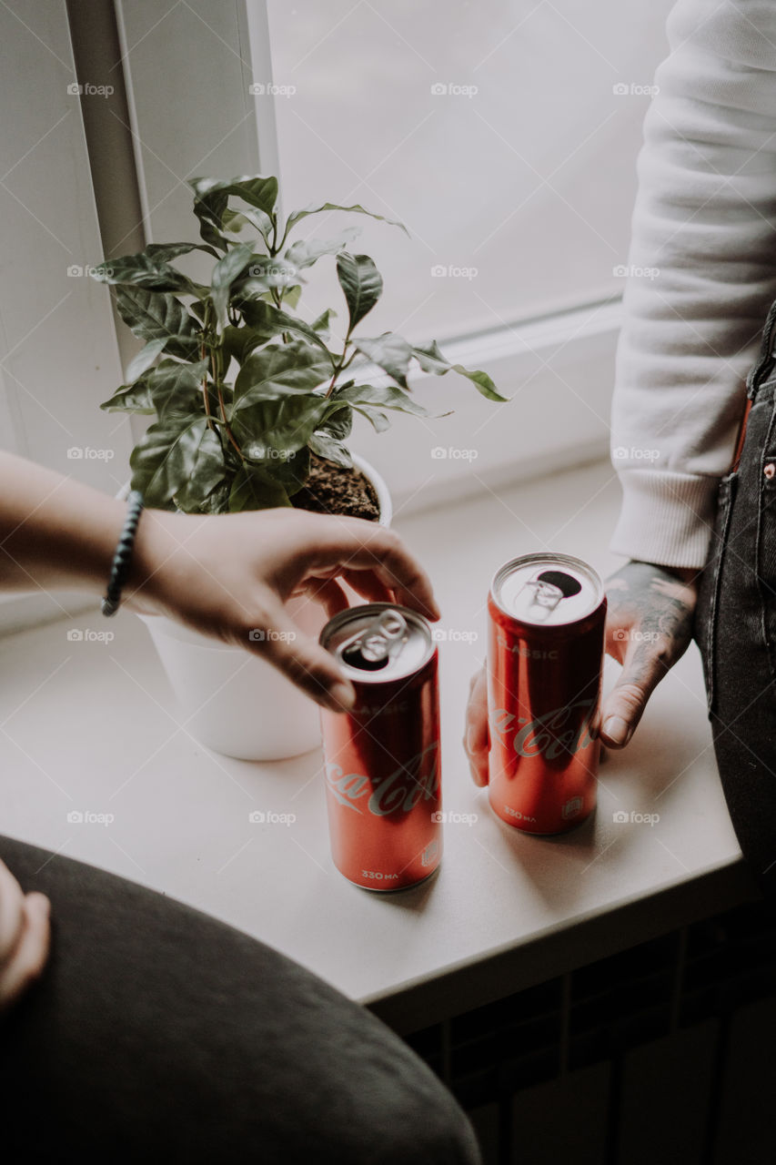 two cans of coca cola and hands in frame