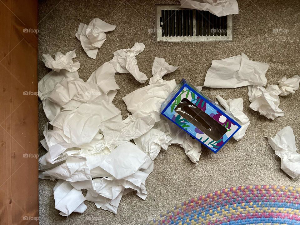 Sick toddler throws a ball inch in front of Kleenex on the floor, making a mess of Kleenex when toddler is sick, learning how to blow their nose 