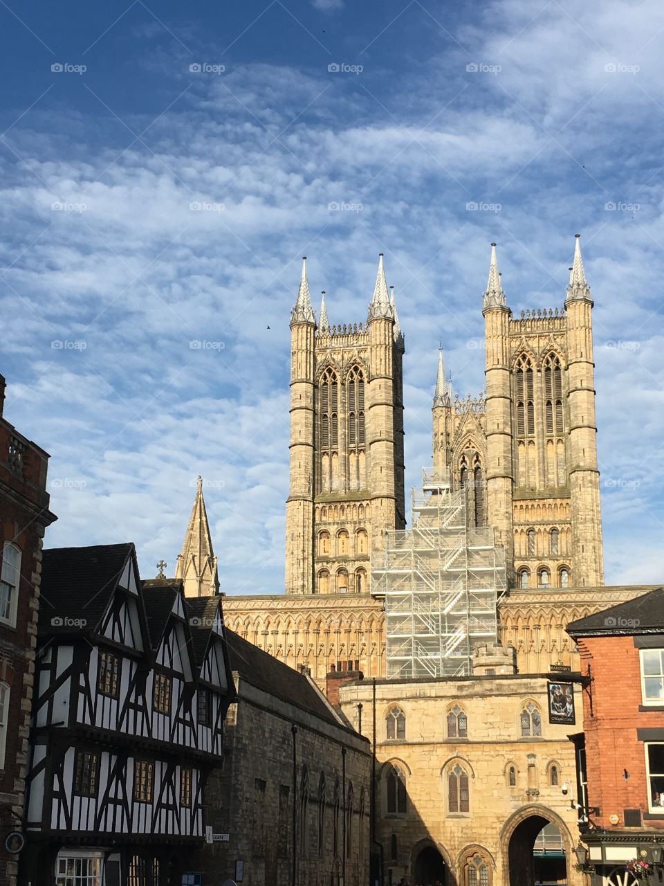 View of Castle Hill and Exchequergate in Uphill lincoln with Leigh-Pemberton house on the left and Lincoln cathedral behind the archway with a summer sky 