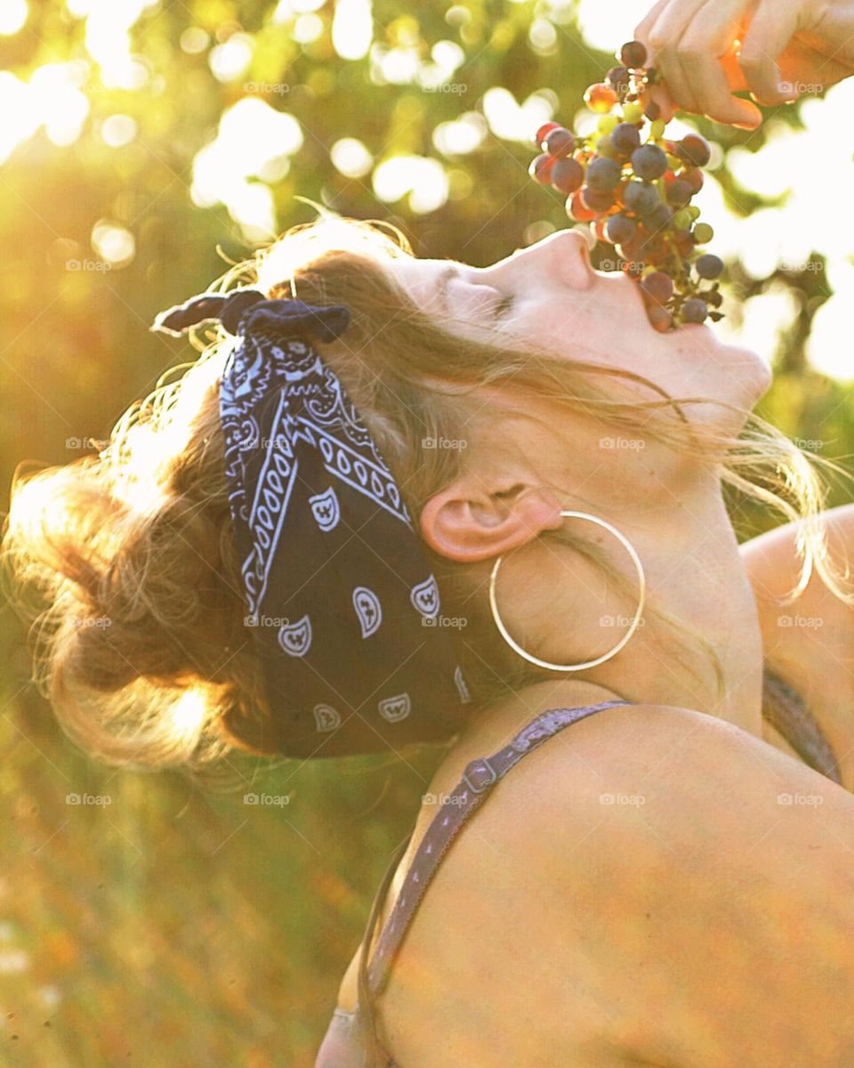 Young woman eating grapes outside in the summer sun
