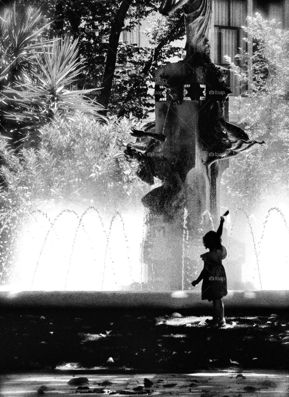 Little girl playing with leafs under the big tree