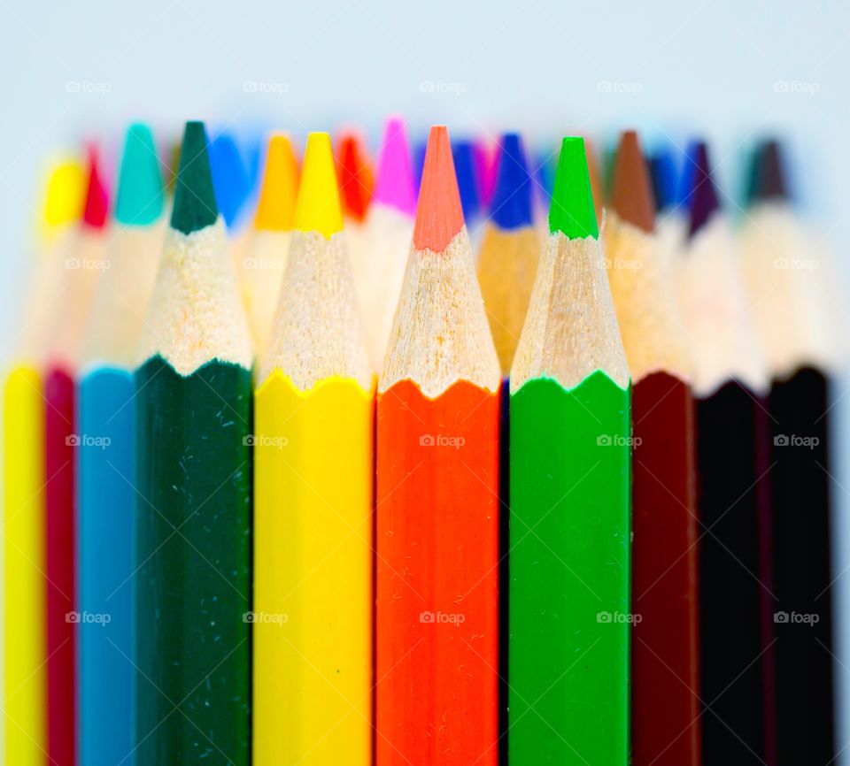 Sharp coloring pencils standing in a group photo with selective focus on green, yellow and red at the front. 