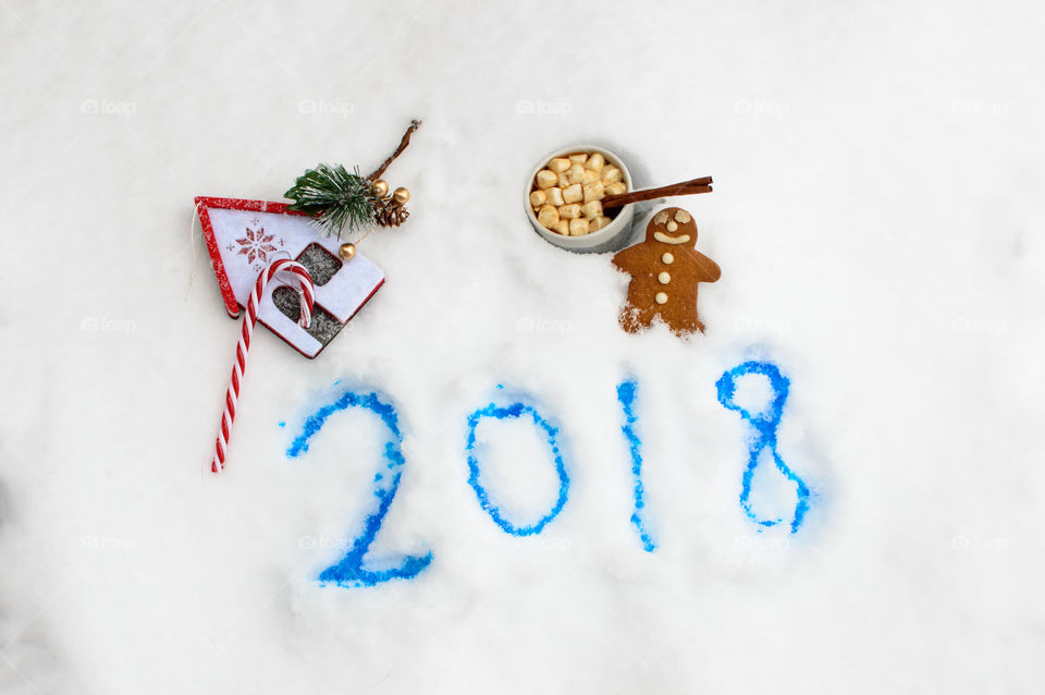Happy new year white Christmas year end 2017 2018 Holiday Christmas vintage gingerbread cookie on fresh snow with hot chocolate with marshmallows next to candy cane ornament traditional Christmas joy and comfort treats on falling snow background with room for copy space  