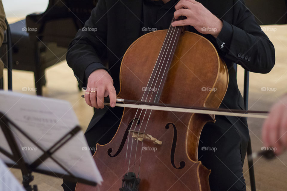 Musician in black plays classical music on a beautiful cello.
