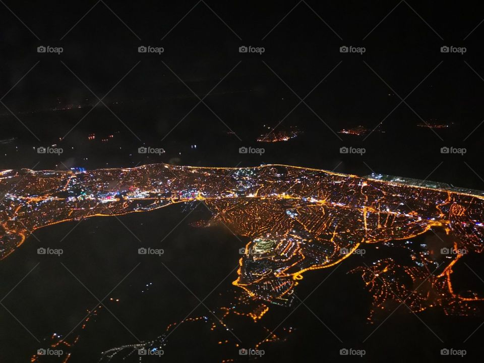Iluminated with lights İstanbul city view from the airplane at night. Black colour on the ground is the sea.