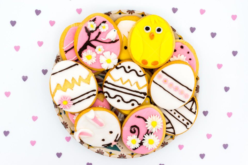 Plate with egg shaped Easter cookies. Fondant figures of flowers, a rabbit and a chick.
