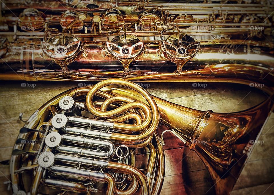 A cornucopia of brass - horn and baritone saxophone on wooden floor 