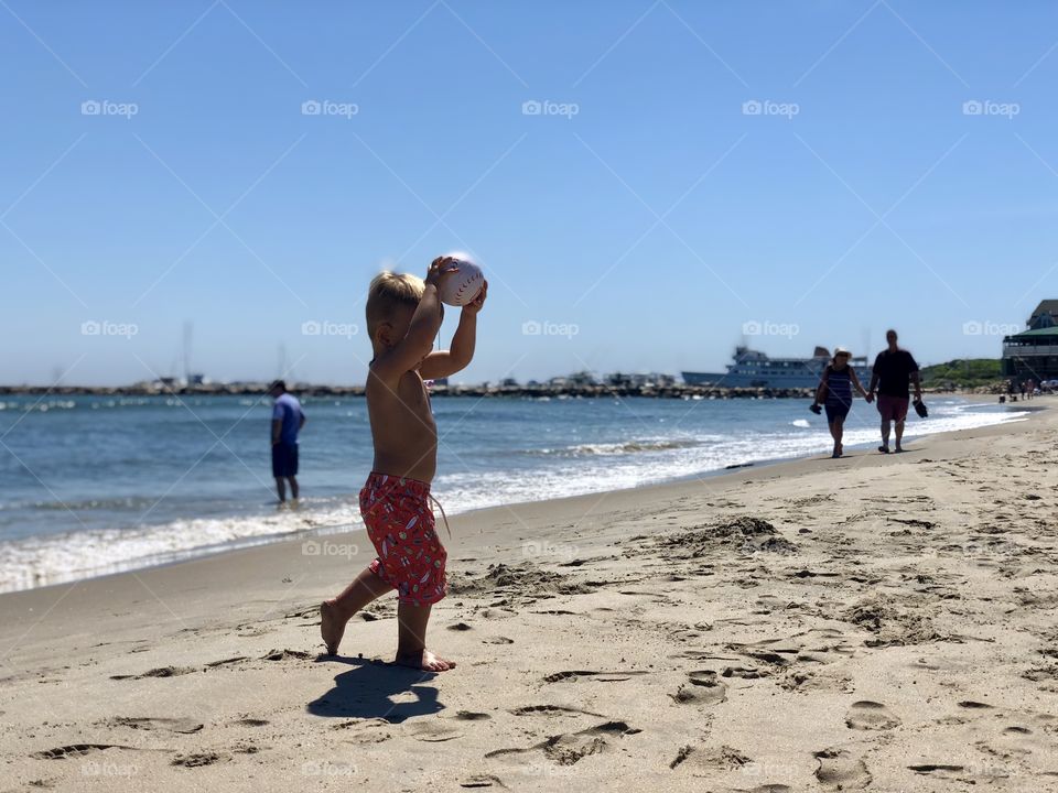 Little boy playing soccer on the beach. 
