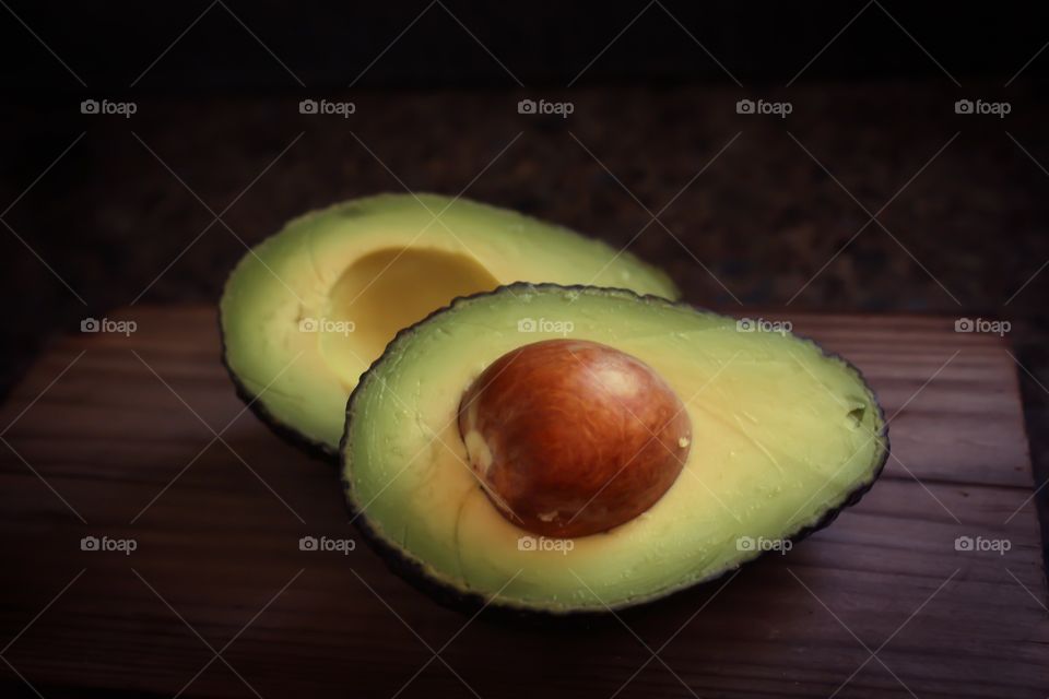 Halved avocado on a wooden chopping board 