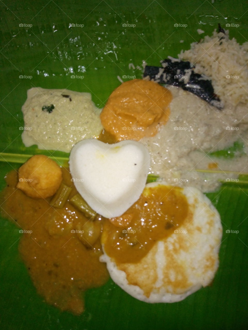 Indian dish idly with chutneys in banana leaf