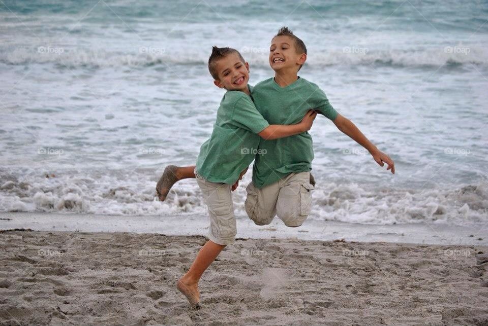 Beach jumpers. Little brothers playing and jumping on the beach 