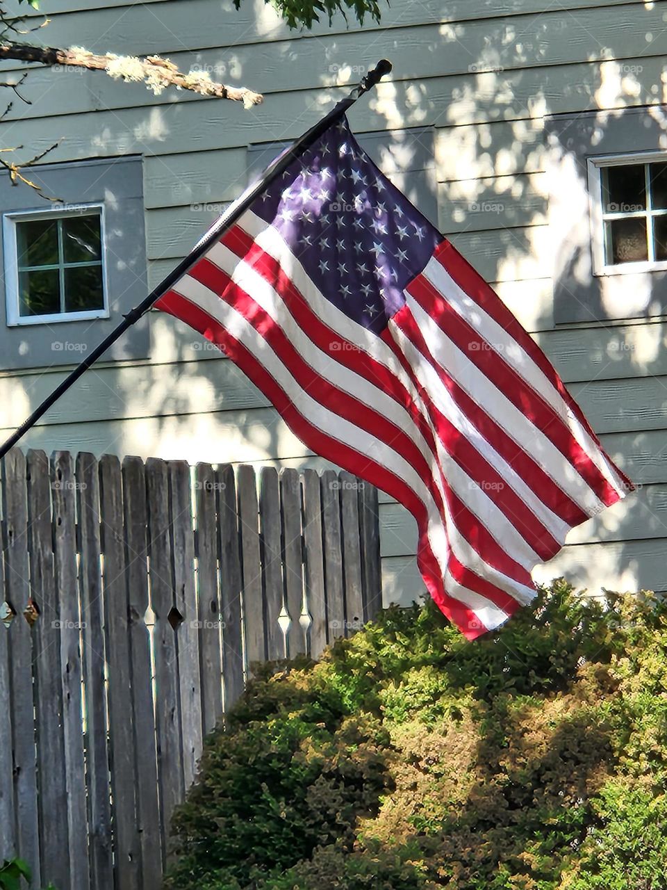 street view of American flag waving in the breeze attached to a Suburban Oregon house fence