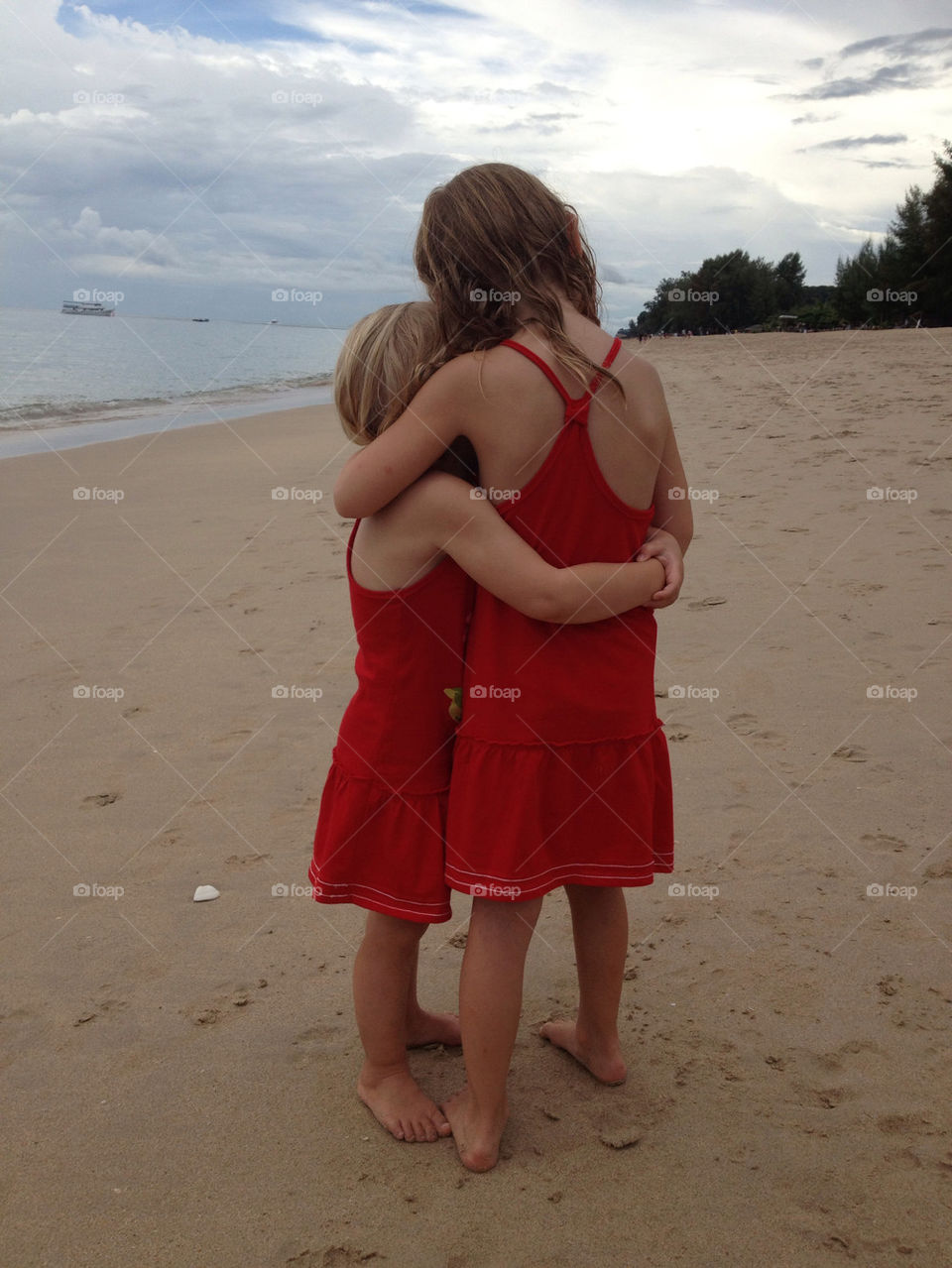 Two sisters hugging and comforting each other on a beach