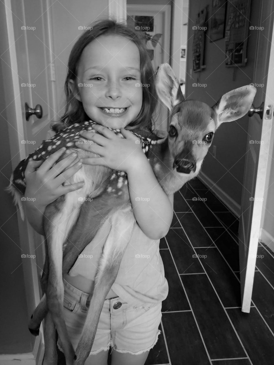 Little girl holding a rescued fawn in her arms before sending him to a sanctuary. orphaned deer