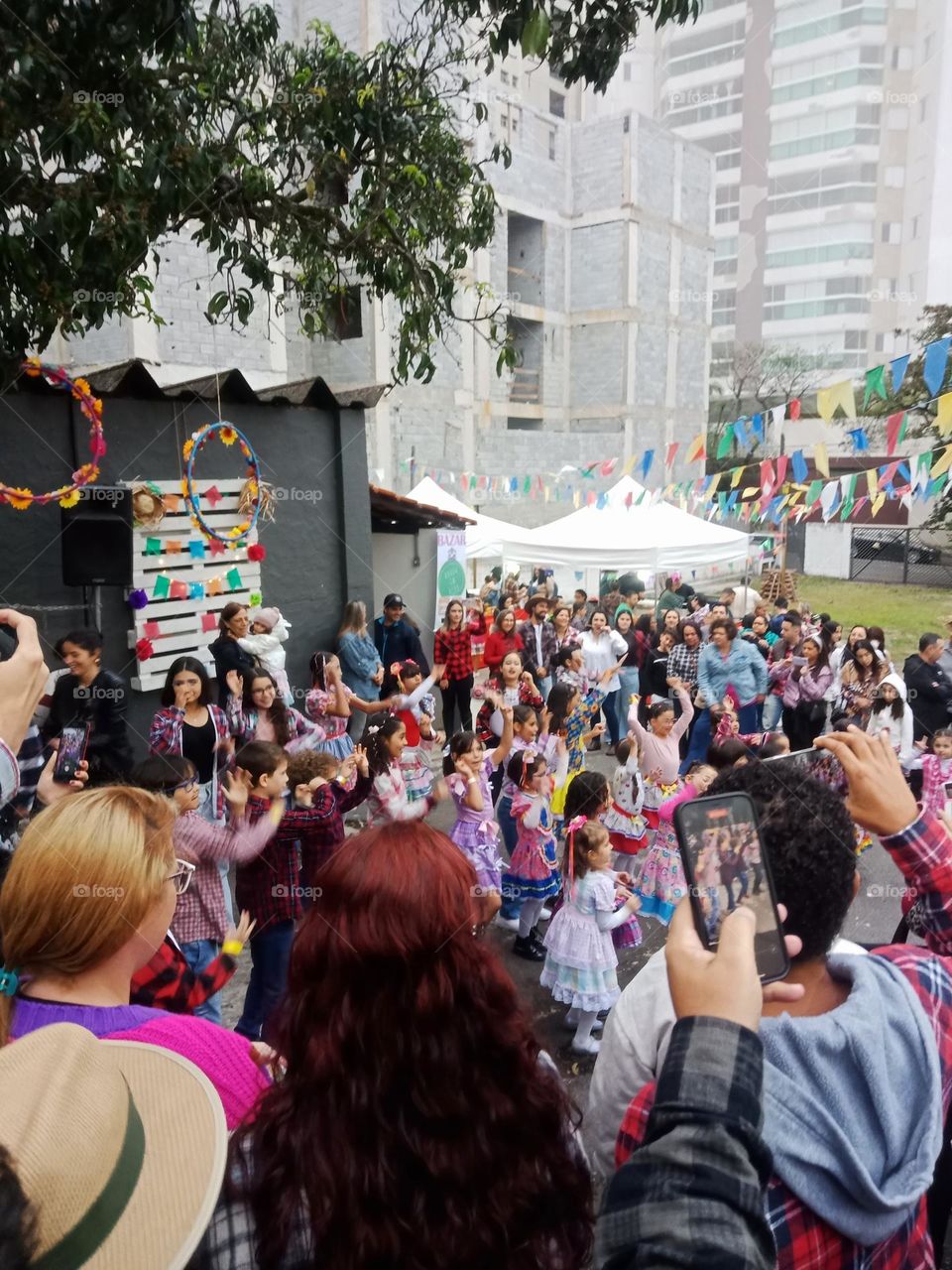 A crowd watching a group of kids dancing in a backyard in a big city