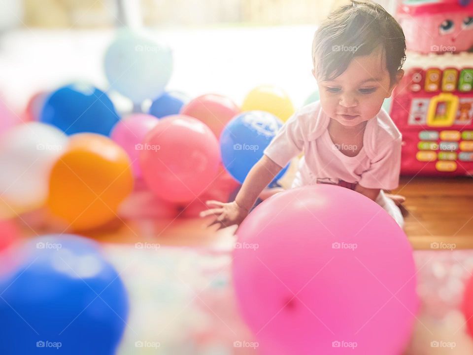 Baby showing emotion of happiness, happy baby with balloons, baby celebrating first birthday, baby with colorful balloons, baby enjoys birthday celebration, baby expressing happiness, the emotions of happiness in a colorful image 