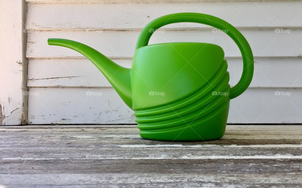 Green Color Story - plastic watering can on wooden porch in shade

