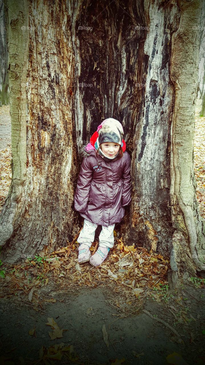 Happy girl sitting on broken tree trunk