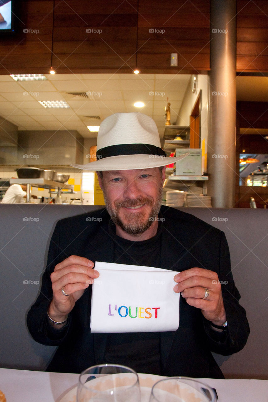 bearded man with a panama hat on holding a napkin that says west in a