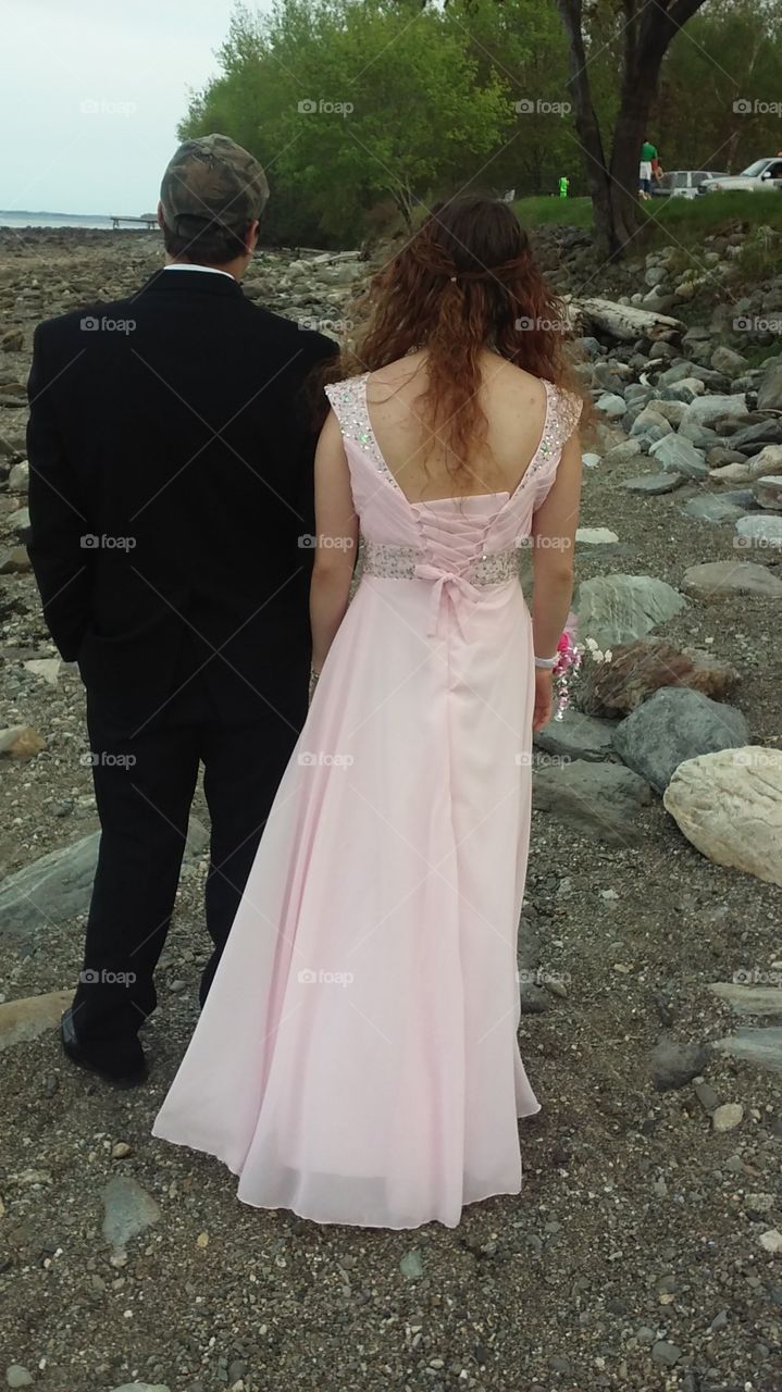 Couple strolling on the beach before their prom.