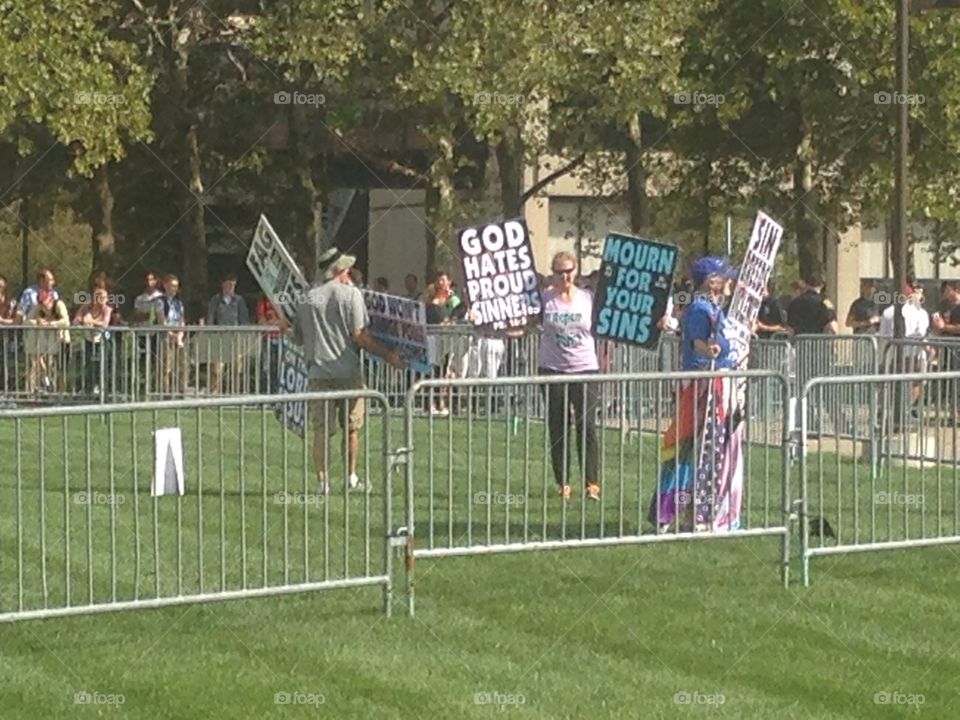 Westboro Baptist church members holding signs to protest an LGB club formed by students of IUPUI.  Club supporters and spectators stand in the background.