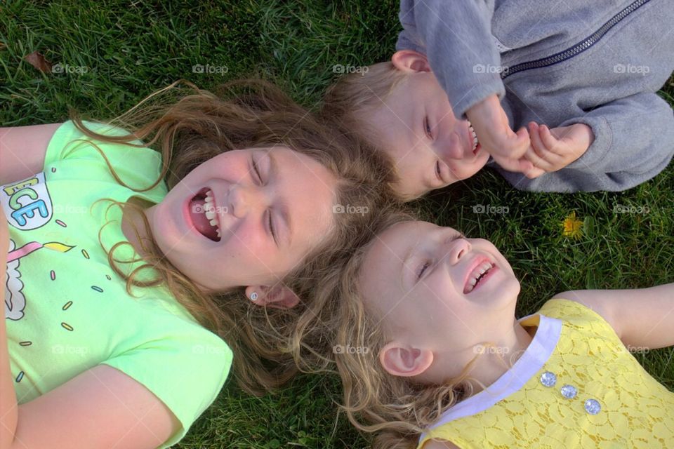 Brother and sisters lying in grass