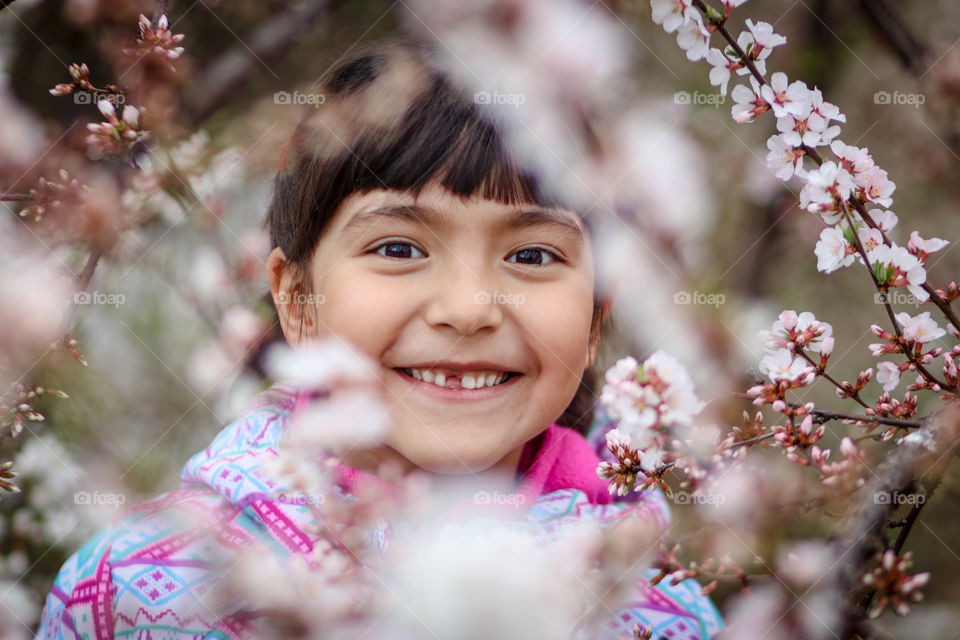 Happy little girl in a blooming cherry tree