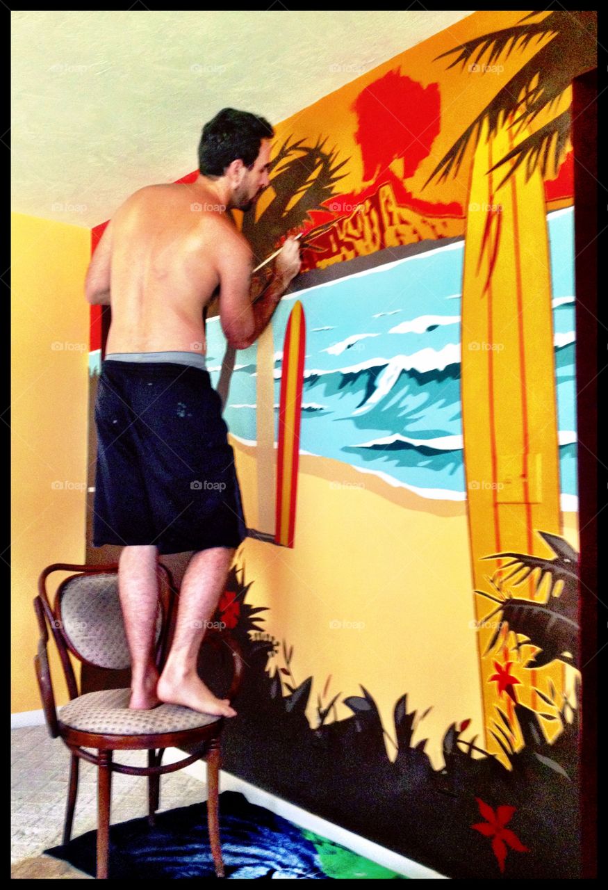 My husband painting a Kona Beer beach scene on our wall
