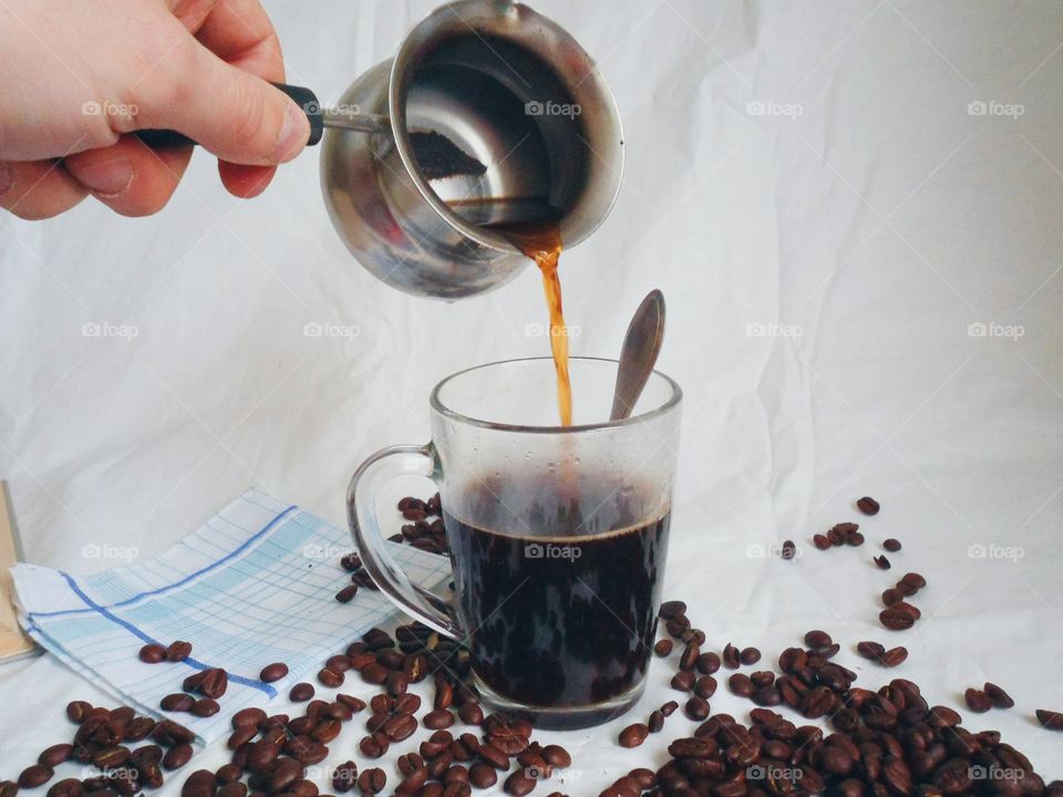 In a cup of coffee poured on the background of coffee beans