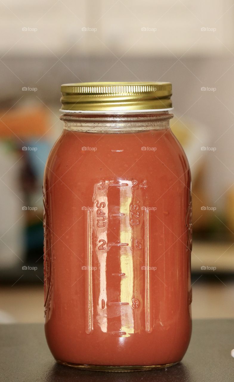 Canning Jar of freshly made quince fruit sauce closeup with kitchen blur background 